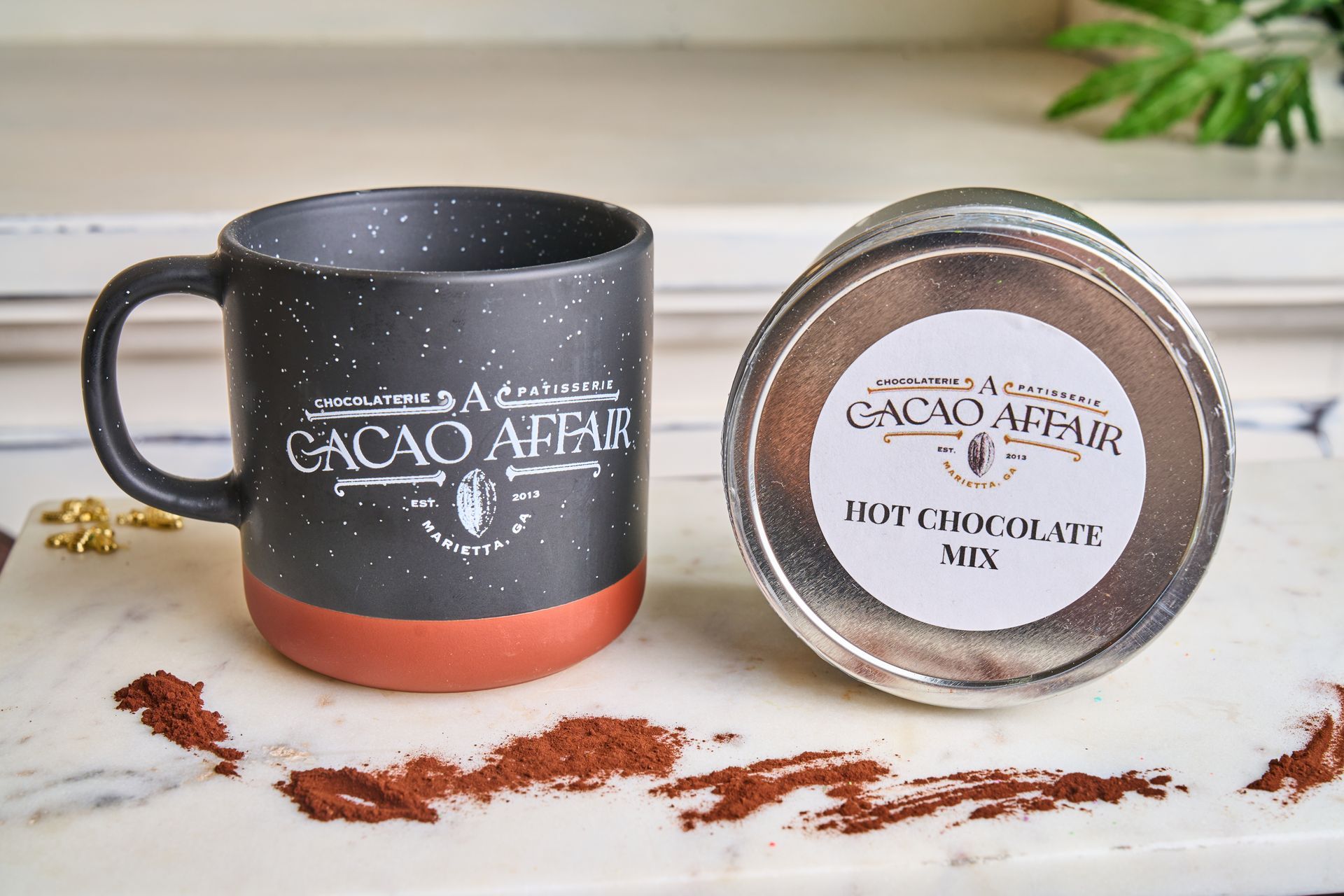 Black and orange speckled mug and tin of hot chocolate mix branded 