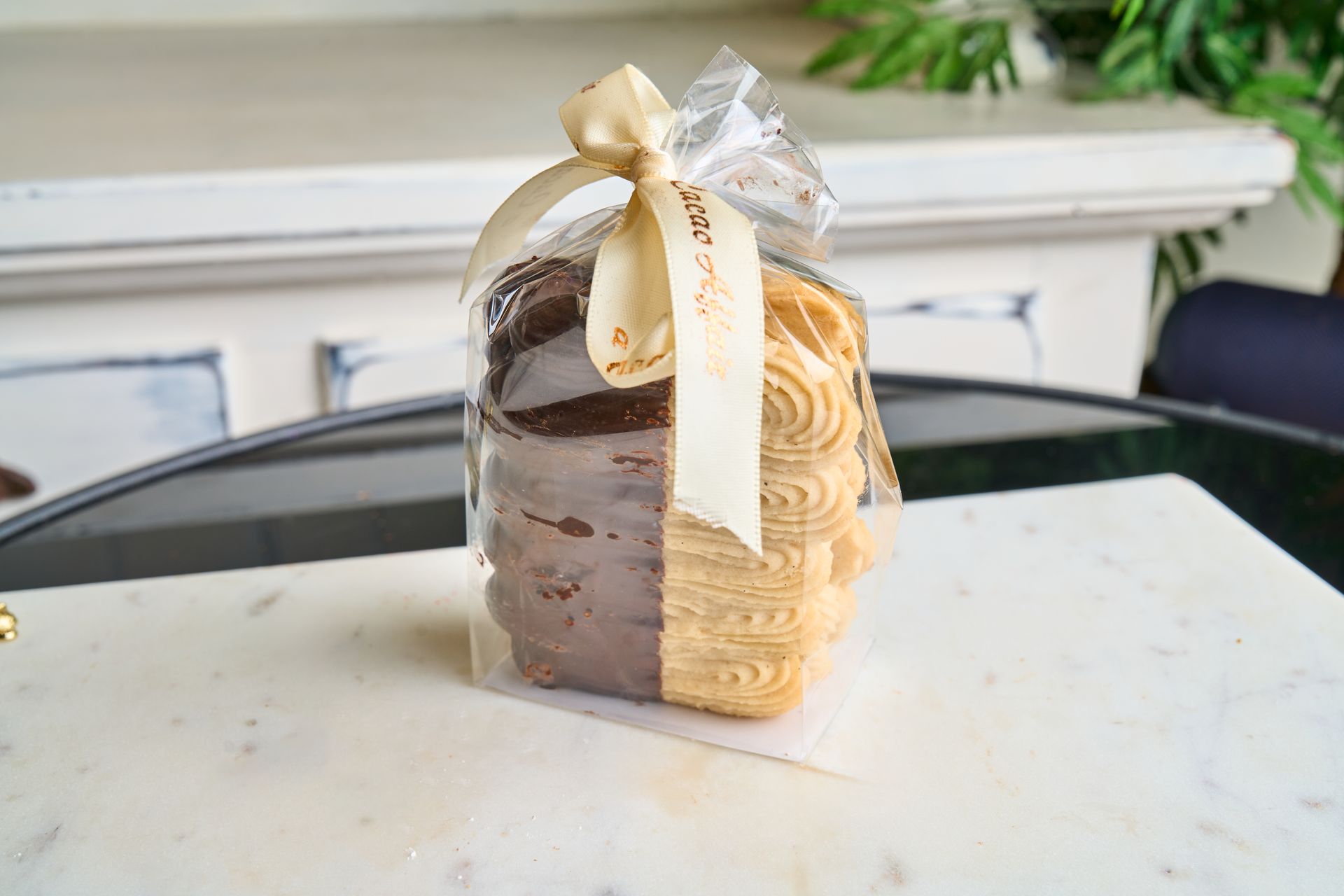 Cookies in clear cellophane tied with a ribbon, on a marble surface.