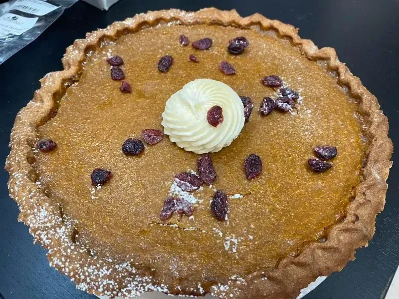 Pumpkin pie with white swirl frosting and cranberries.