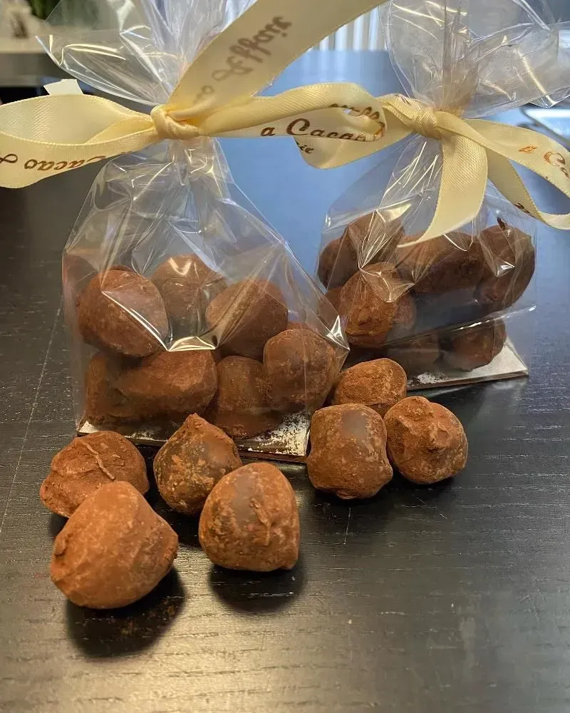 Two bags of chocolate truffles, tied with ribbons, and scattered truffles on a dark surface.