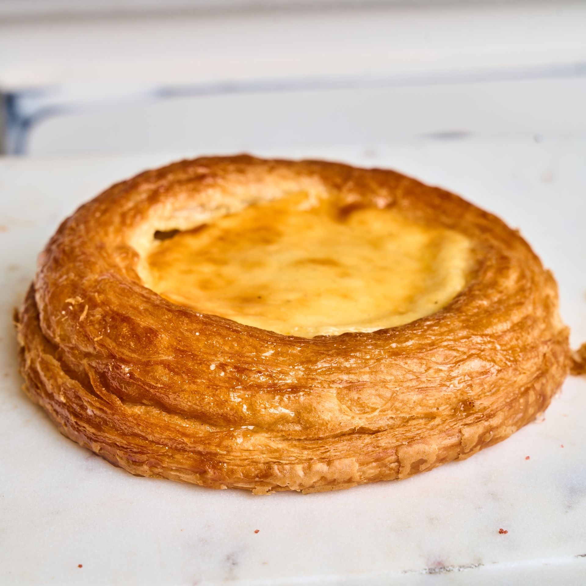 Round pastry with a custard center, on a white surface.