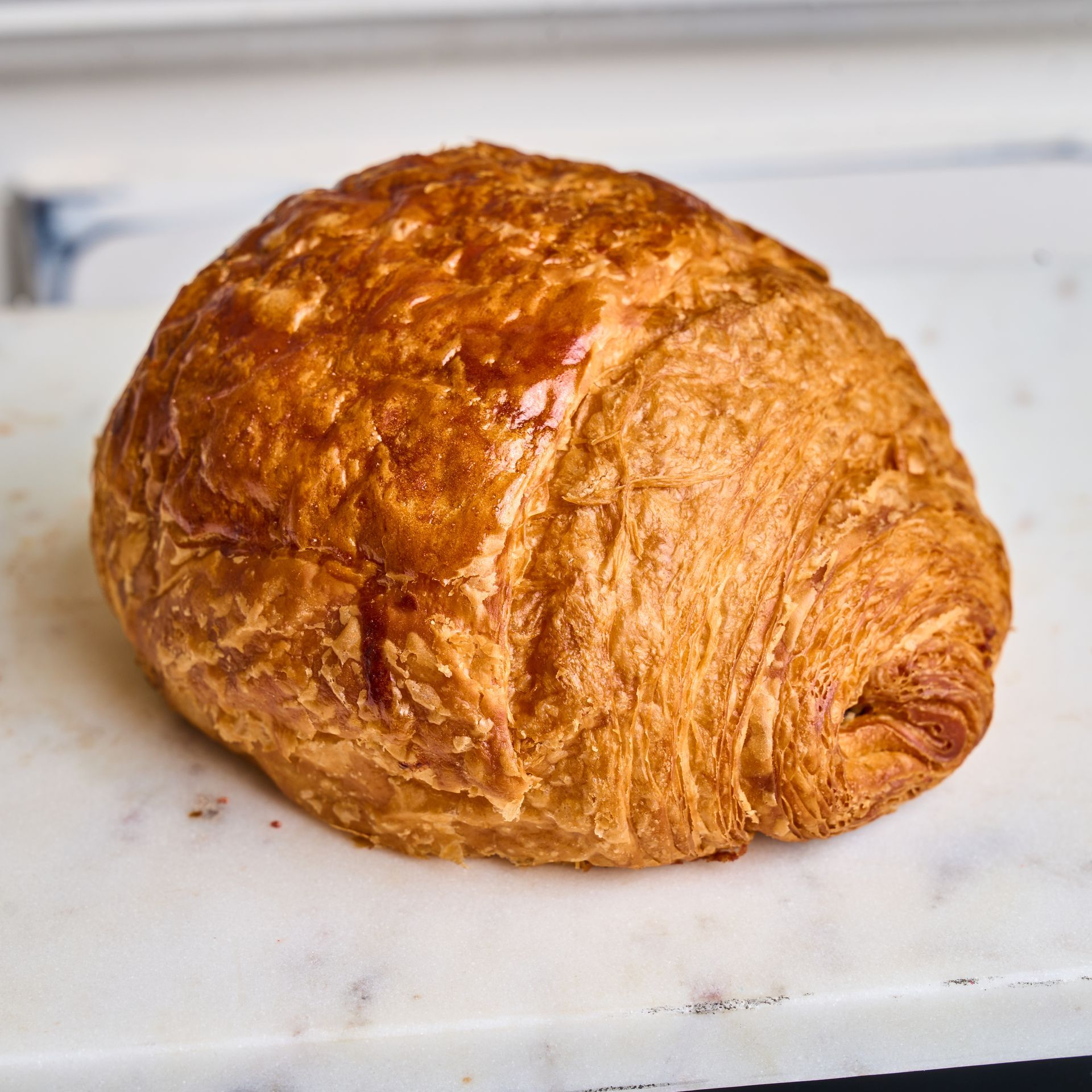 Golden, flaky croissant on a marble surface.