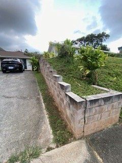 A car is parked in a driveway next to a brick wall