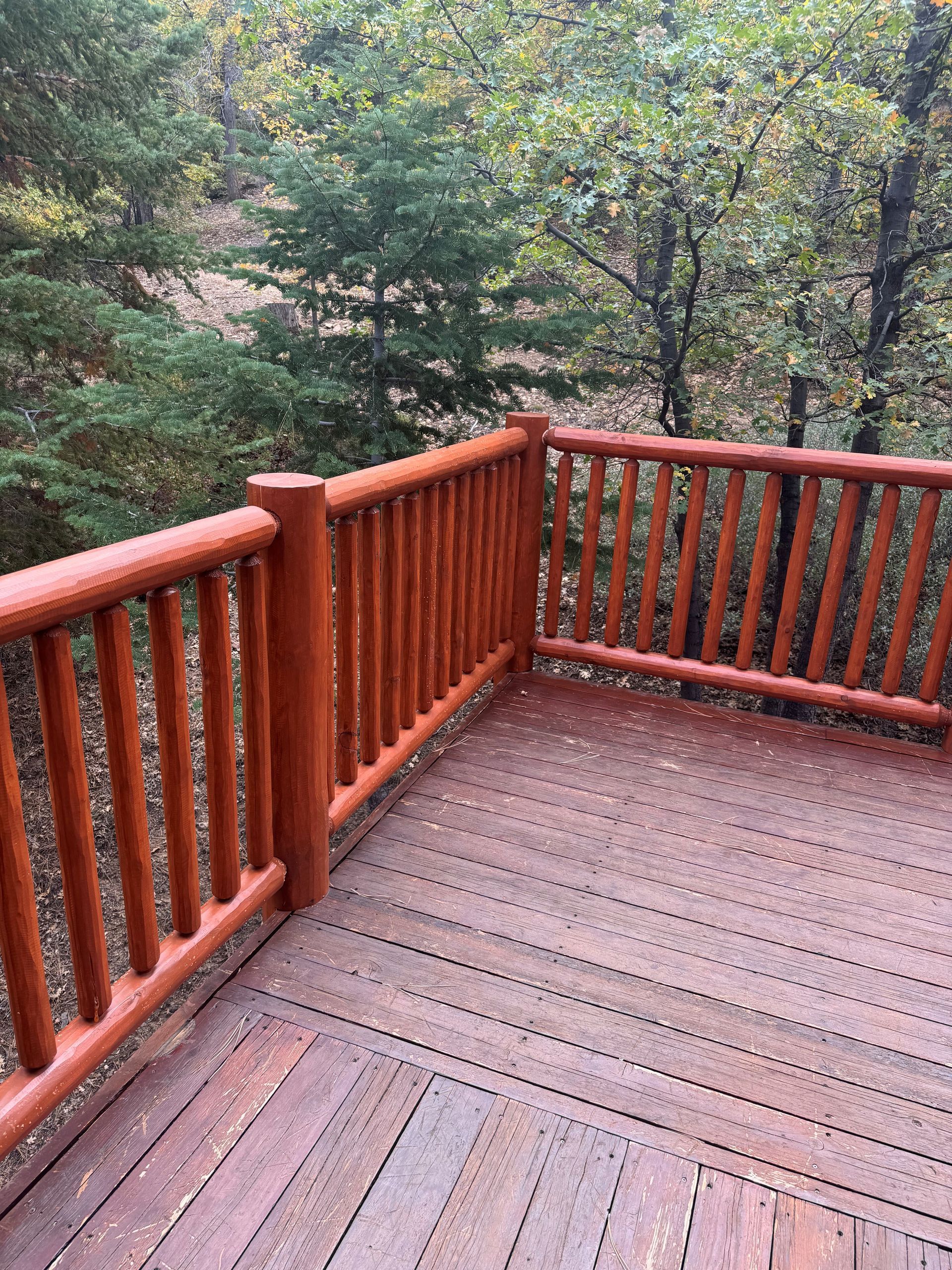 Wooden deck with a railing overlooking a forest.