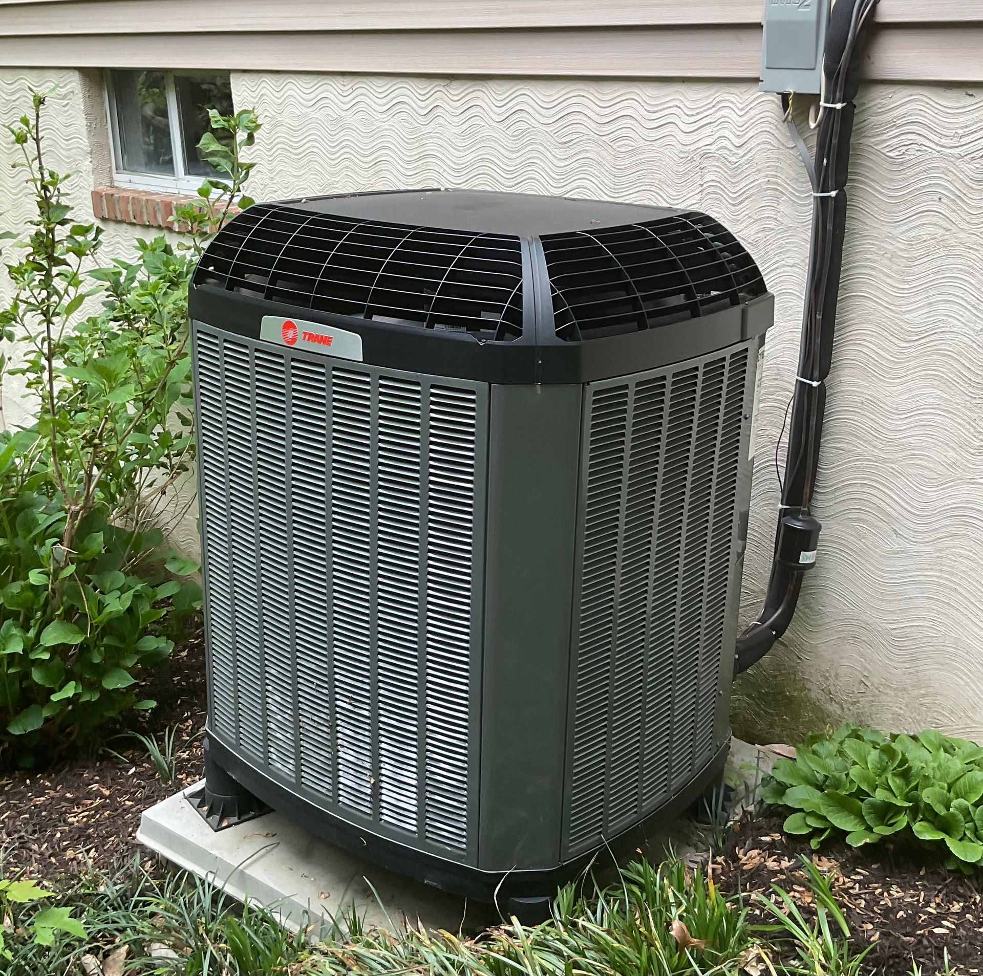 Wall-mounted air conditioner unit on a red brick building exterior