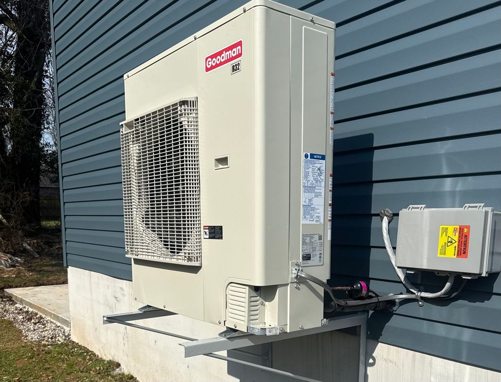 Outdoor AC unit beside a red brick house with shrubs and a screened patio in the yard
