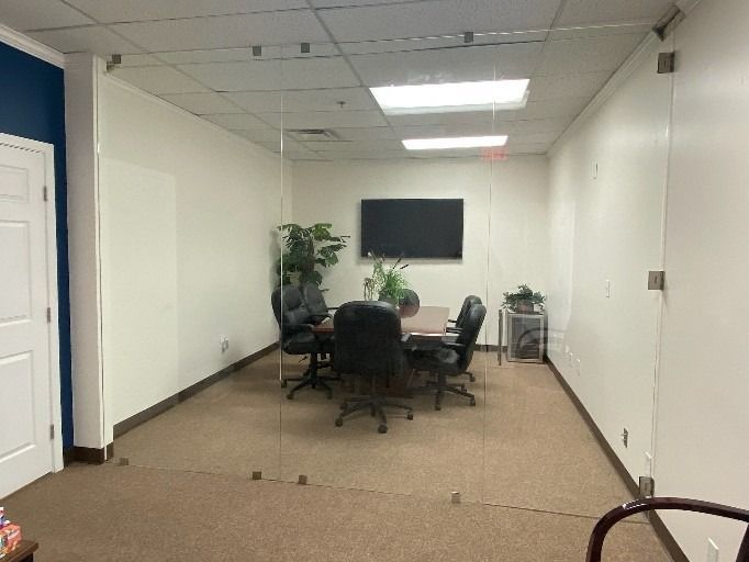 A conference room with a table and chairs and a flat screen tv.