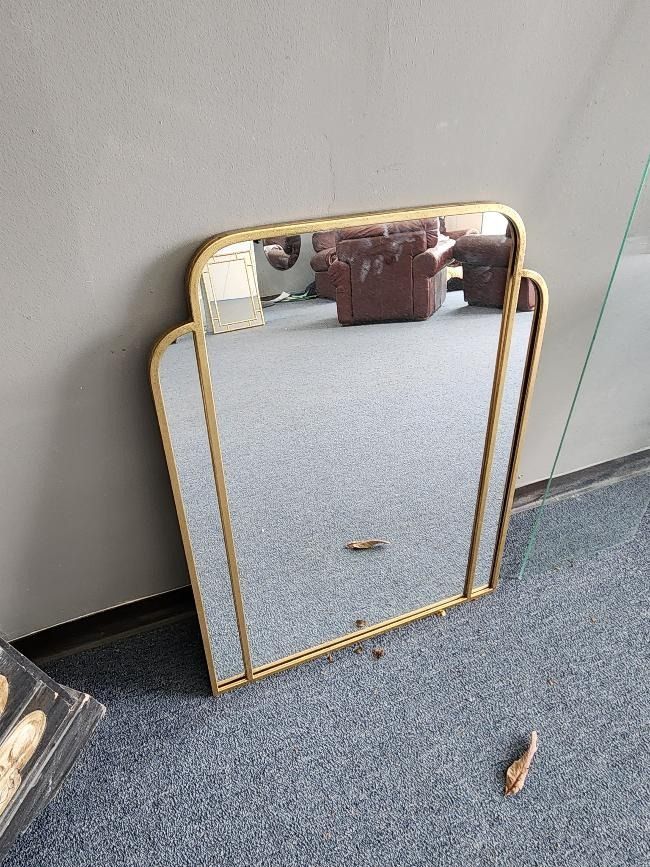 A large mirror is sitting on the floor in a room.
