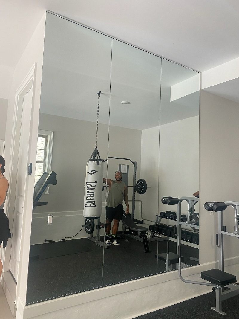 A man is standing in front of a large mirror in a gym.