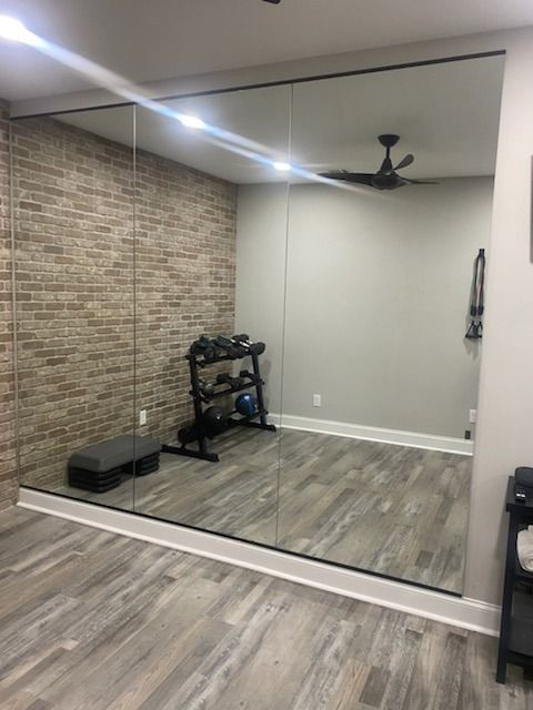 A room with a large mirror on the wall and a ceiling fan.