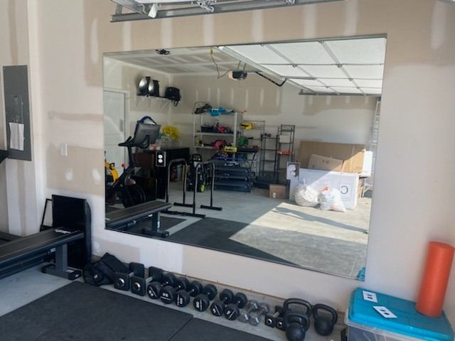 A gym with a large mirror and a bunch of dumbbells