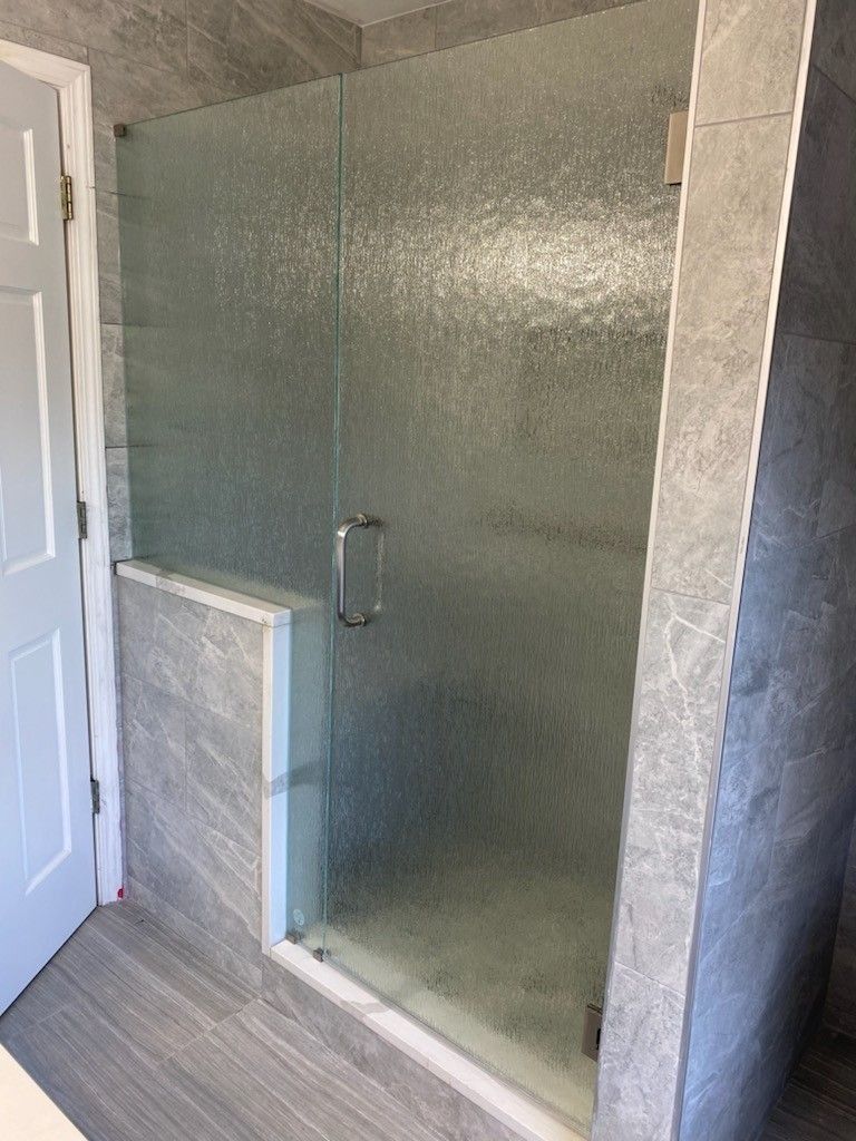 A bathroom with a glass shower door and a white door.