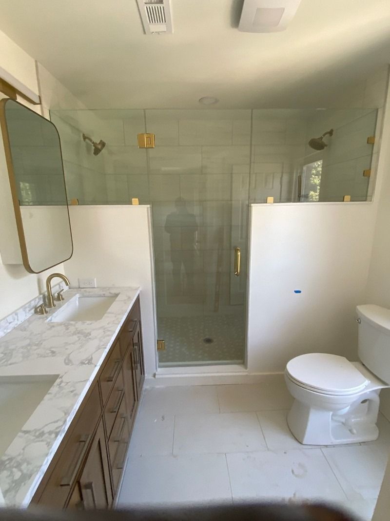 A bathroom with a sink , toilet , shower and mirror.