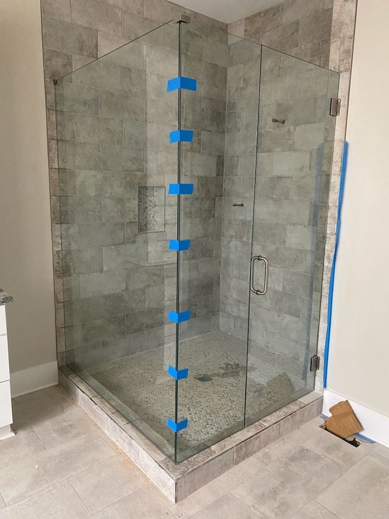 A shower stall with a glass door is being built in a bathroom.