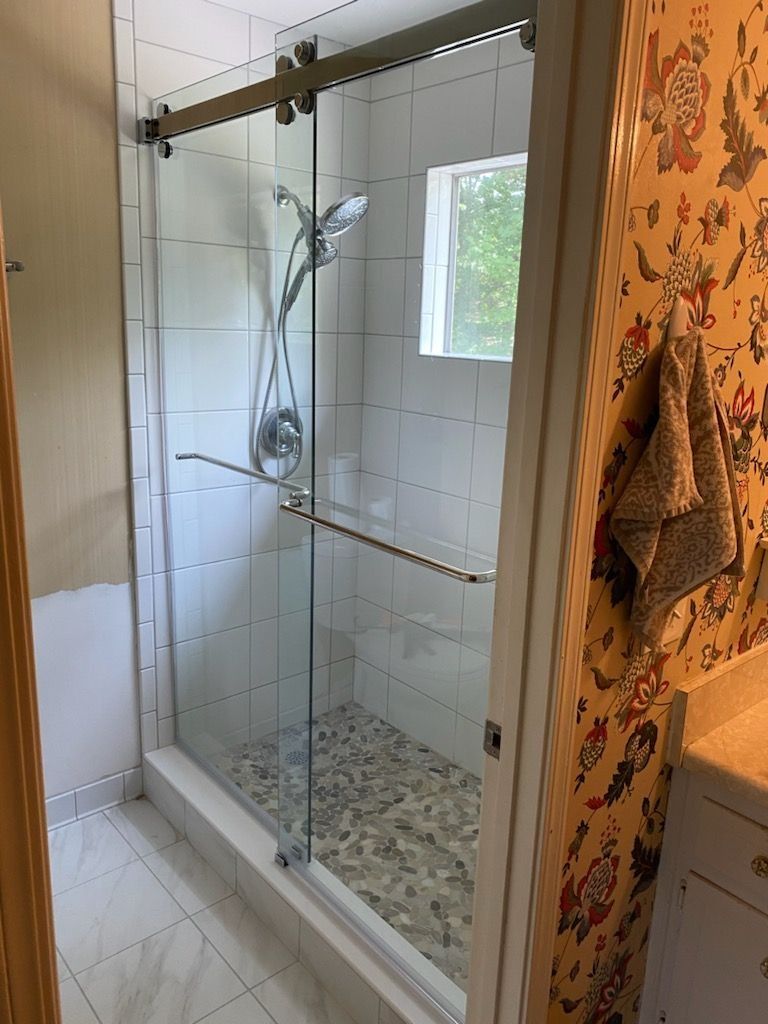 A bathroom with a sliding glass shower door and a window.