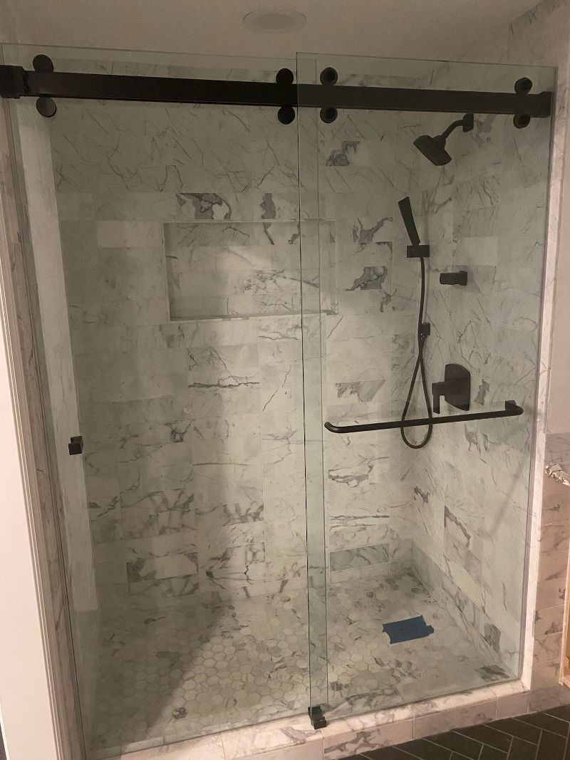 A shower stall with a sliding glass door and a shower head.