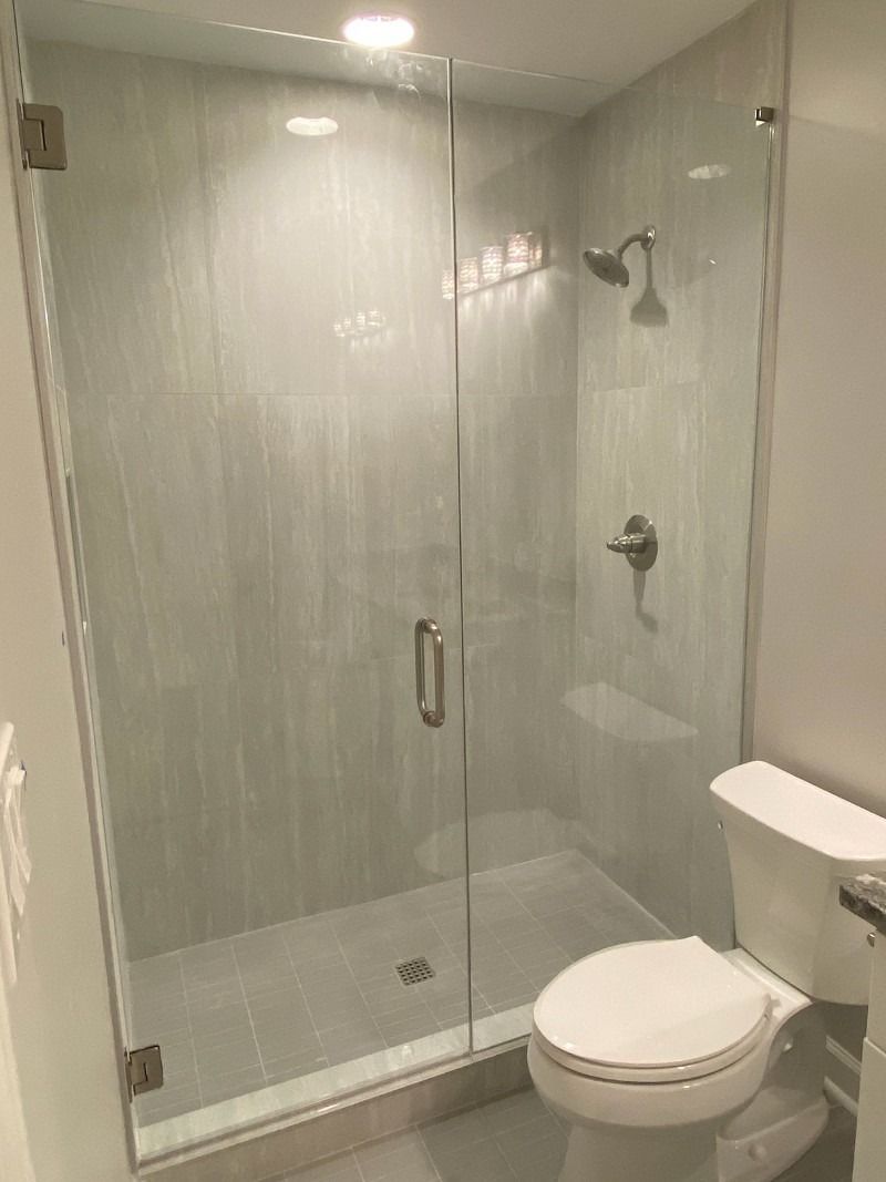 A bathroom with a toilet , shower and glass door.