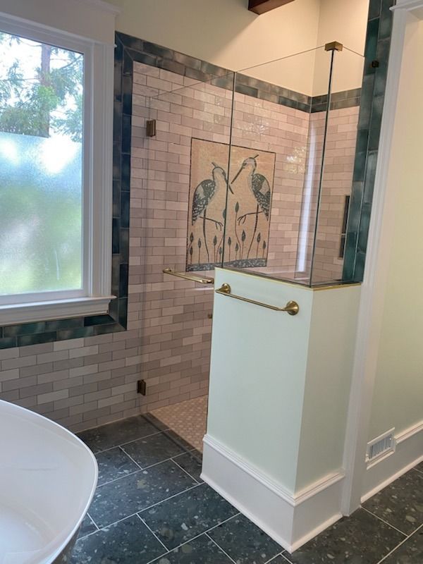 A bathroom with a walk in shower and a window.