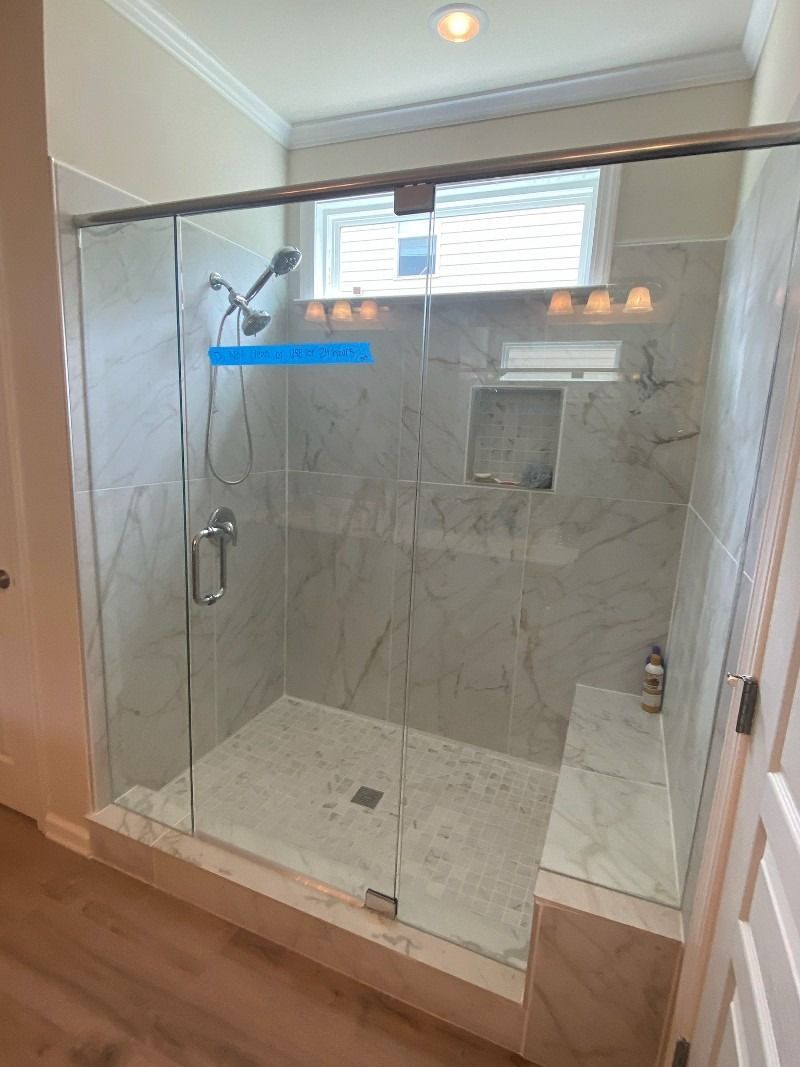 A bathroom with a sliding glass shower door and a window.
