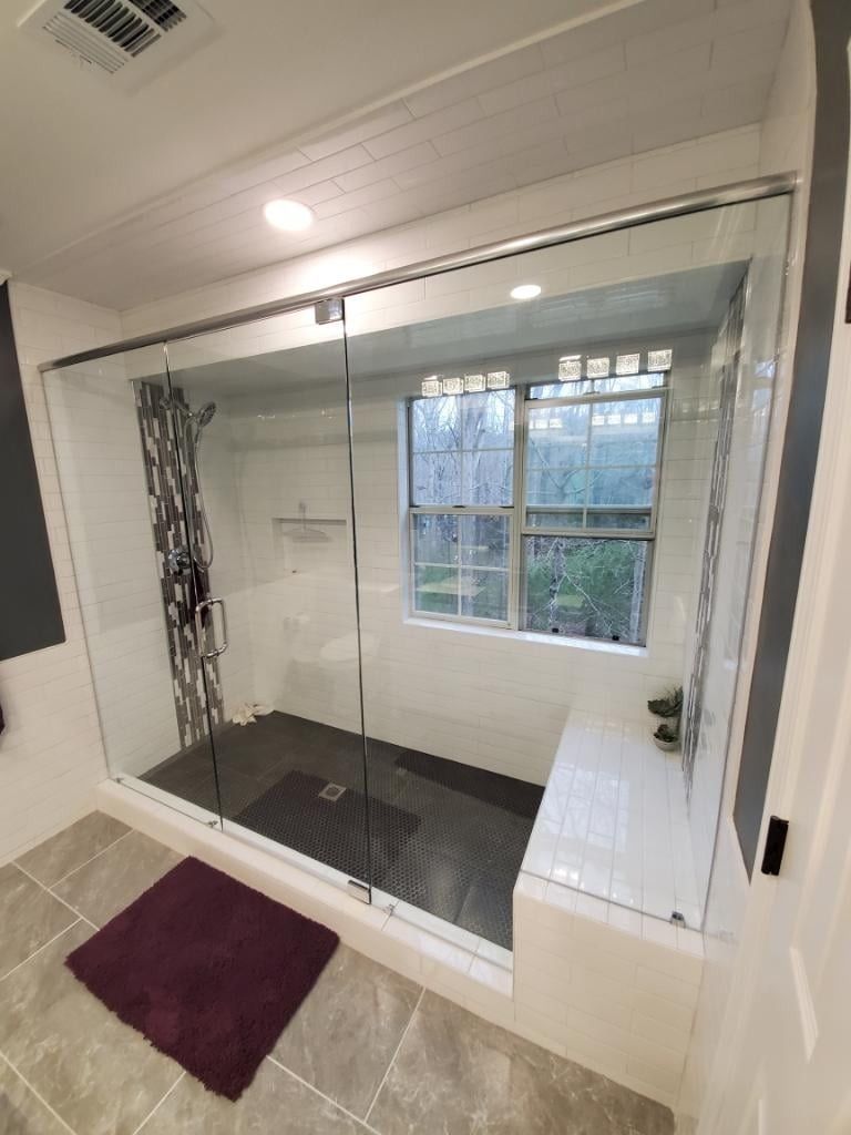 A bathroom with a walk in shower and a window.