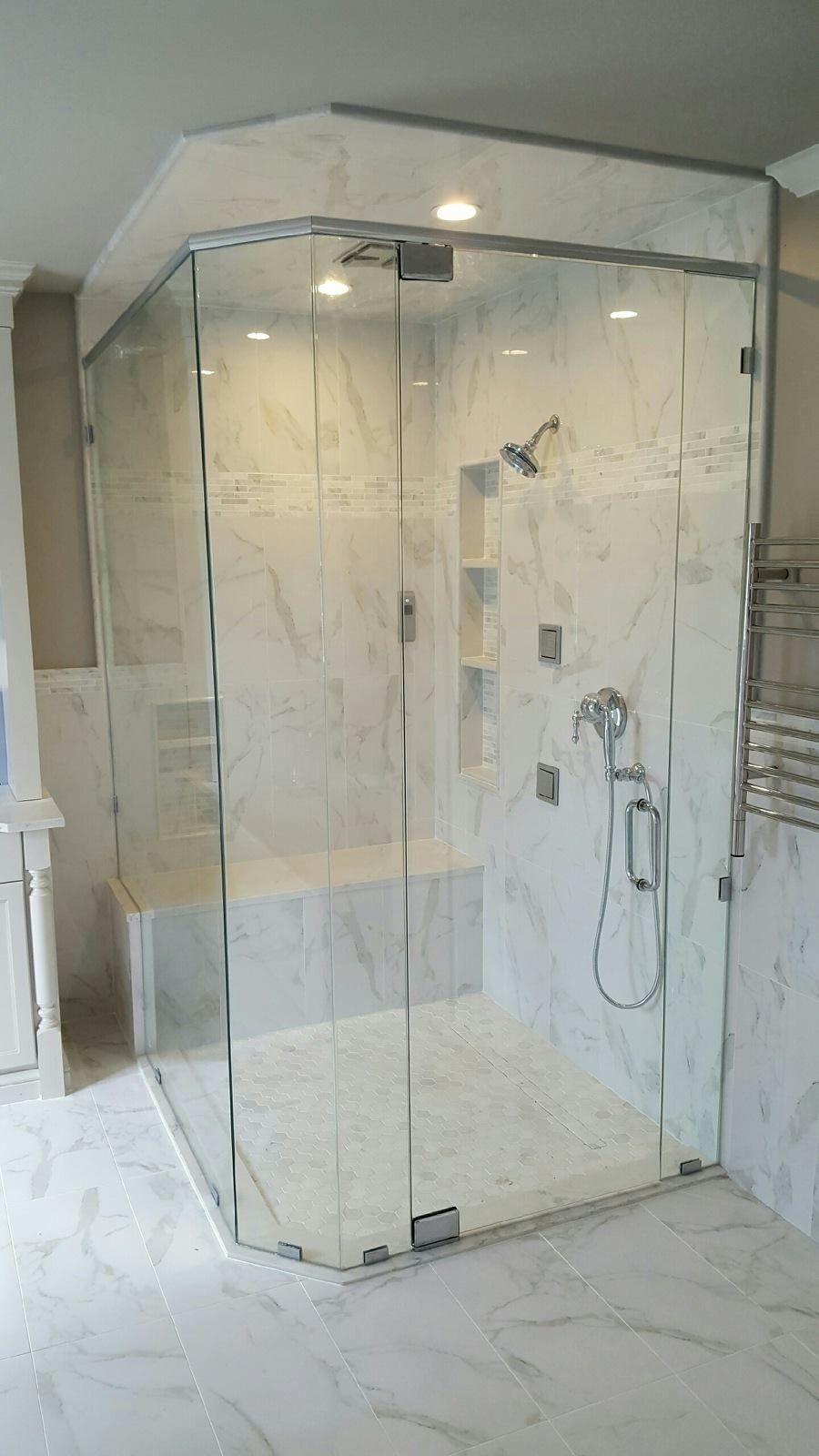 A bathroom with a walk in shower with a glass door.