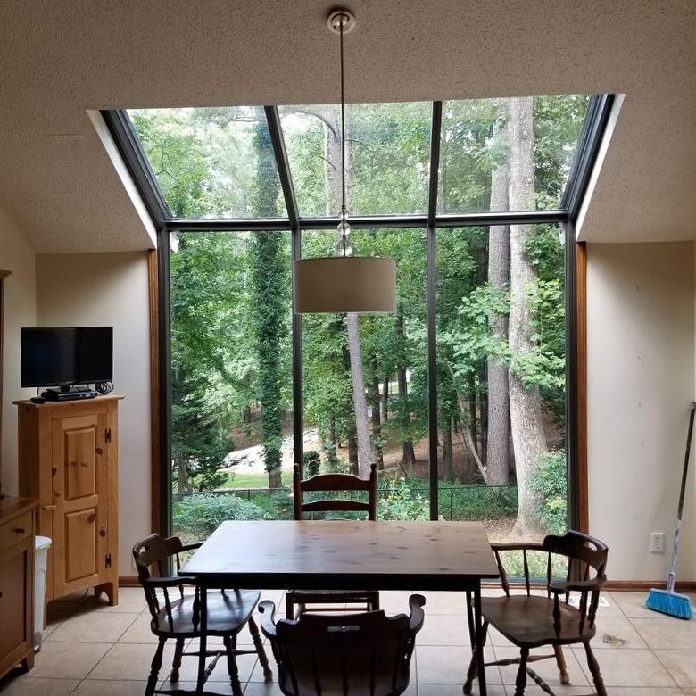 A dining room with a table and chairs and a view of trees