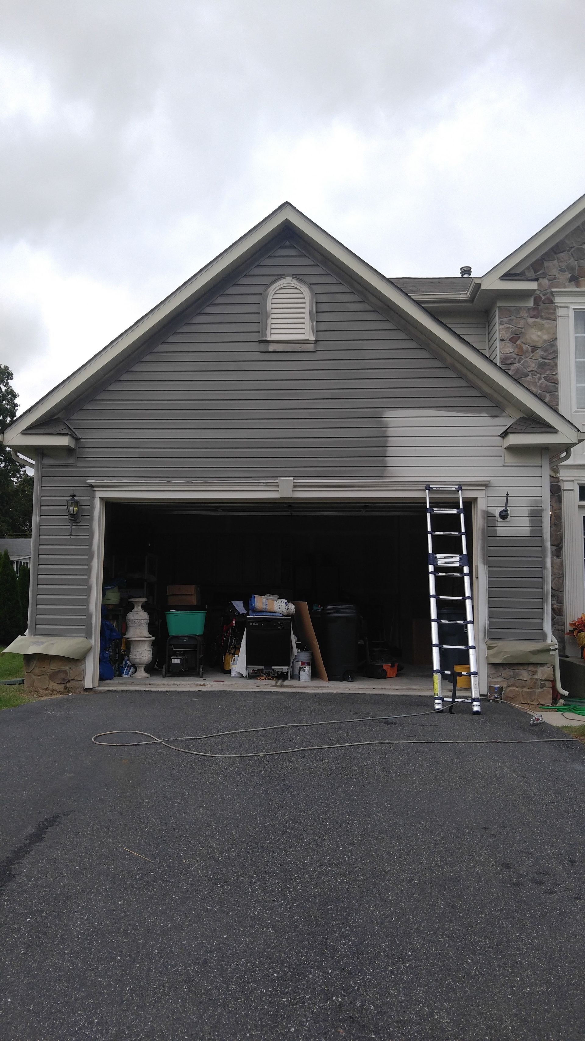 A garage door is being painted in front of a house.