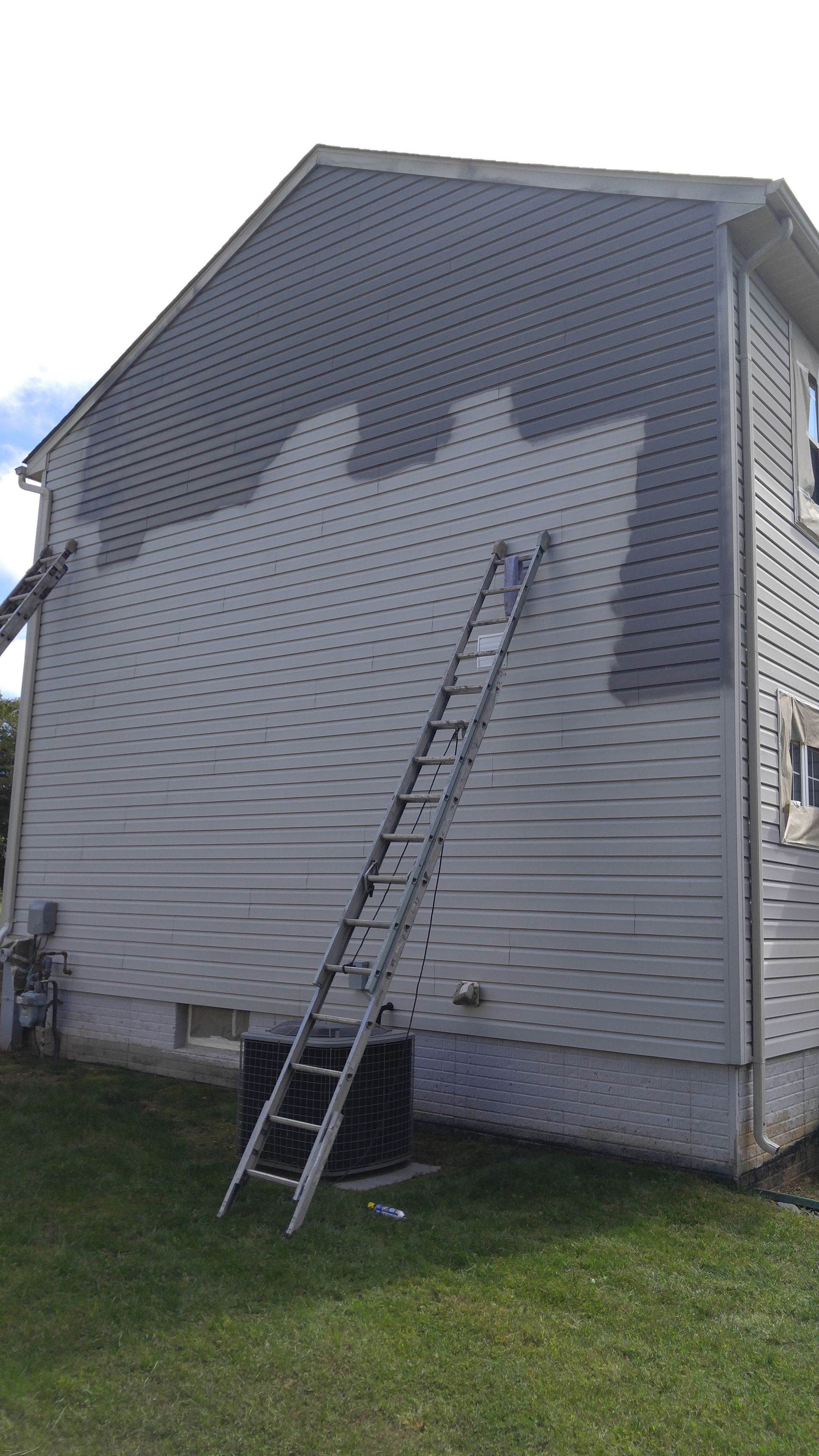 A house is being painted with a ladder attached to it.