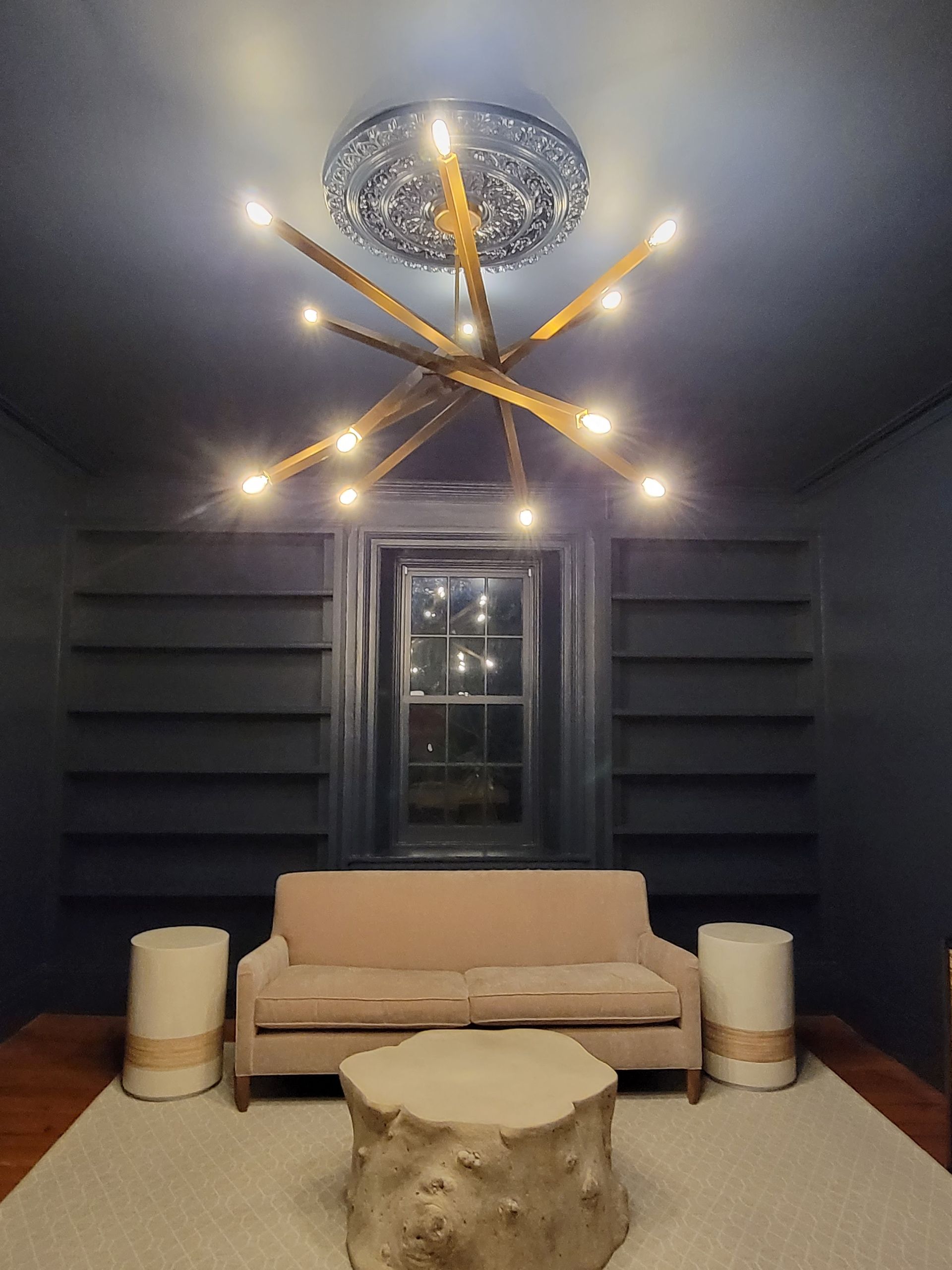 A living room with a couch and a chandelier hanging from the ceiling