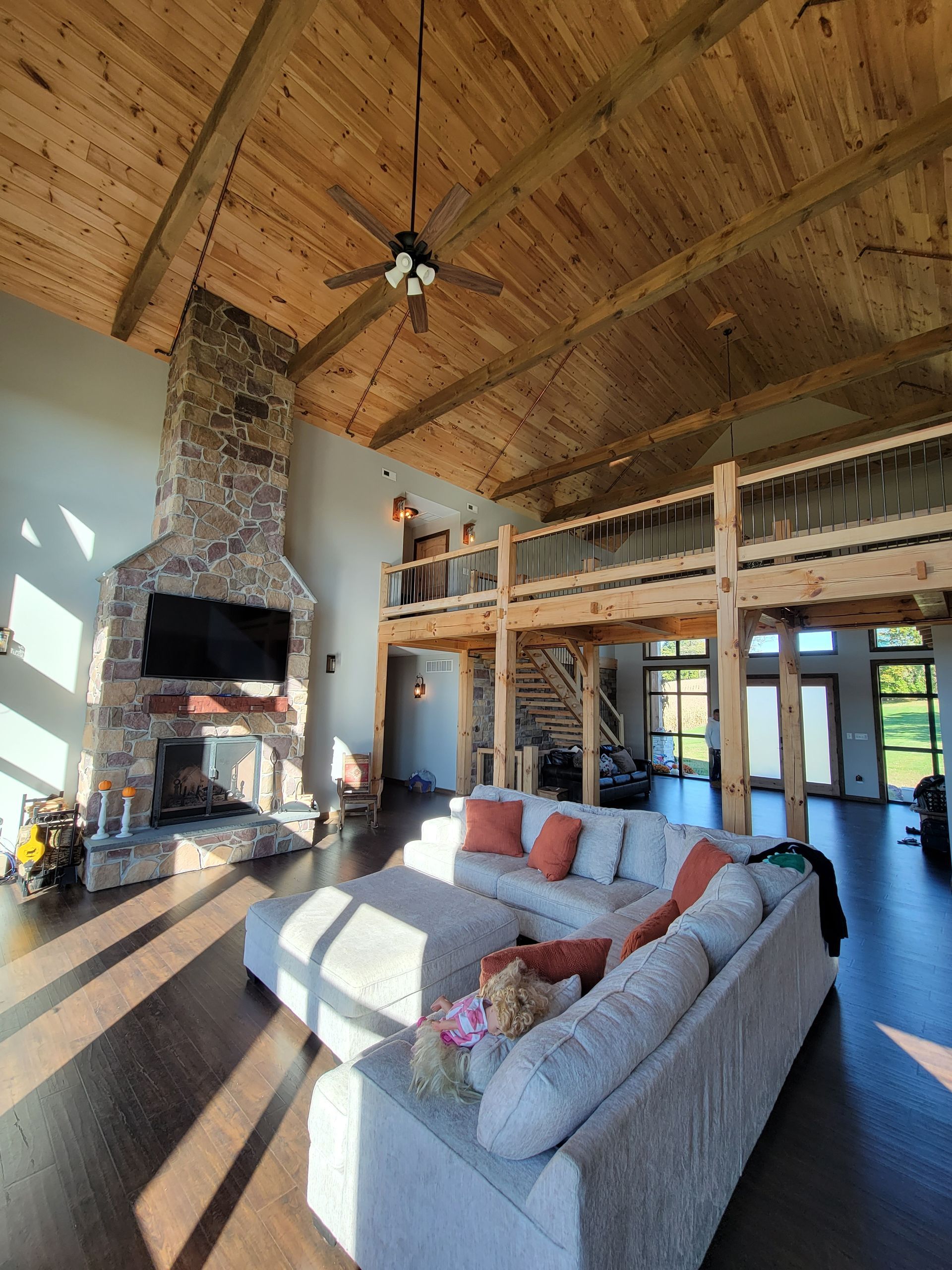 A living room with a couch , fireplace , television and ceiling fan.