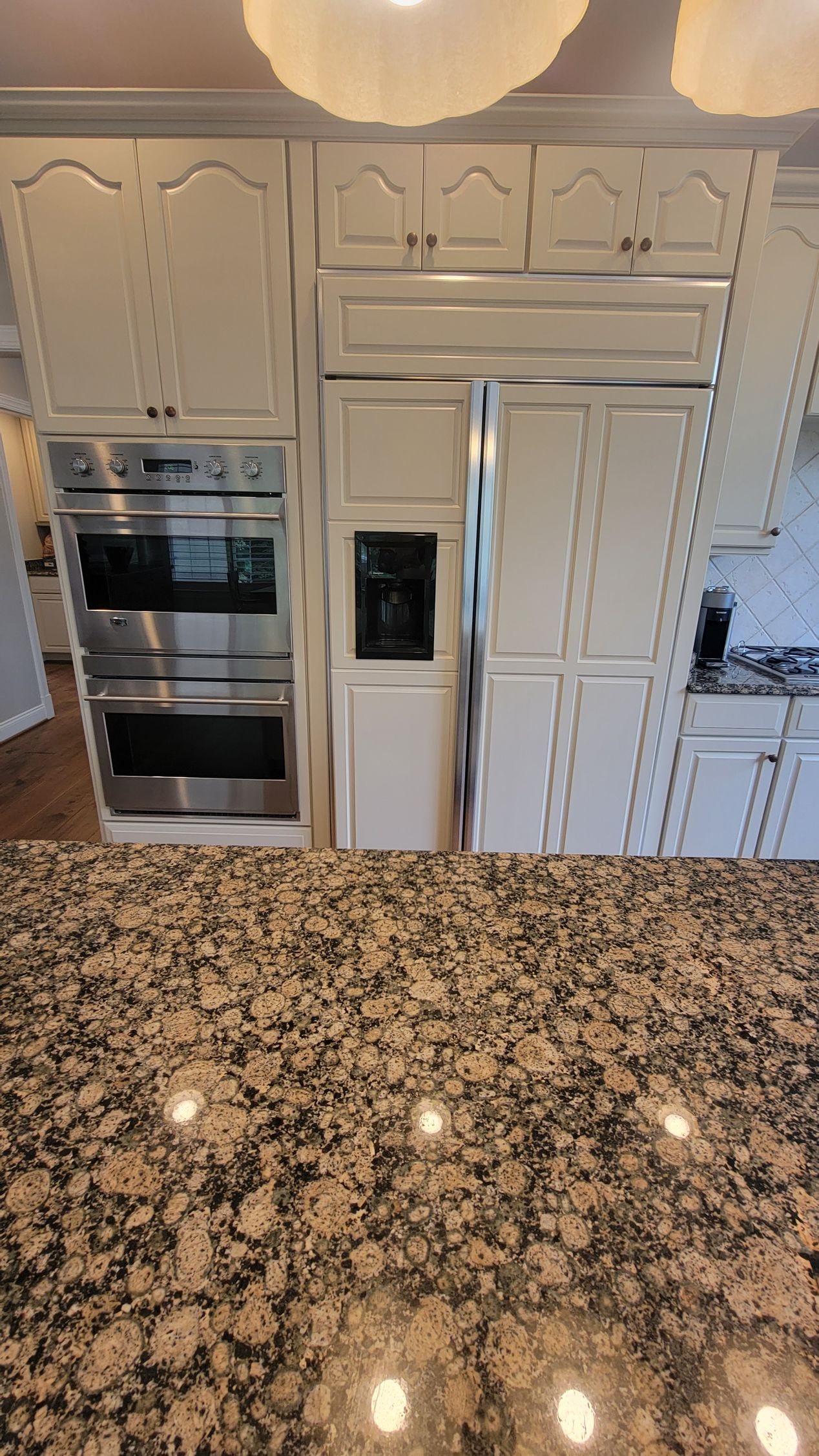 A kitchen with white cabinets , stainless steel appliances and granite counter tops.