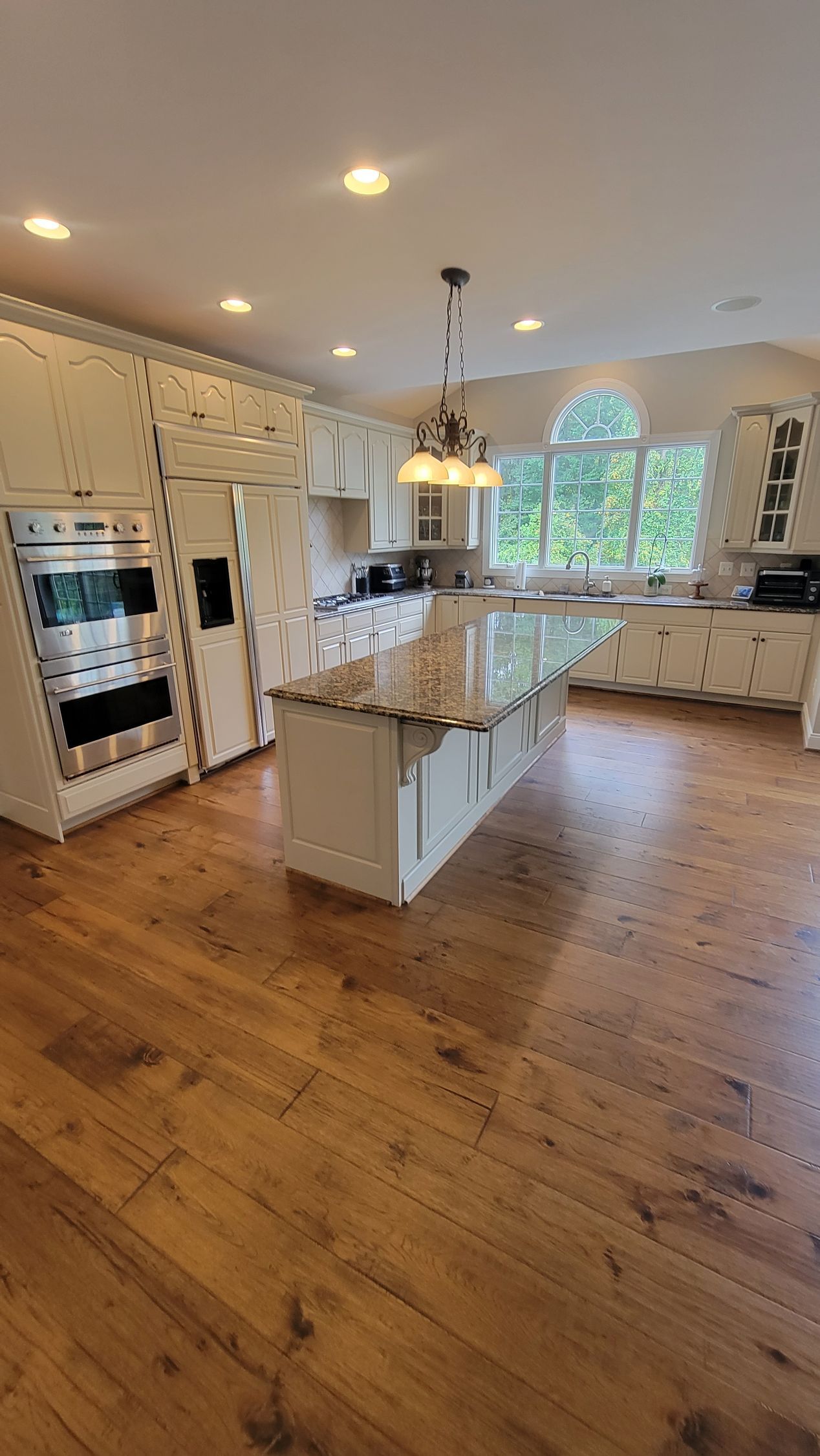A large kitchen with hardwood floors and white cabinets.