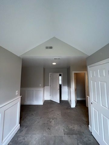 A hallway in a house with a vaulted ceiling and a tiled floor.