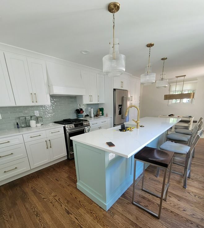 A kitchen with white cabinets and a large island in the middle