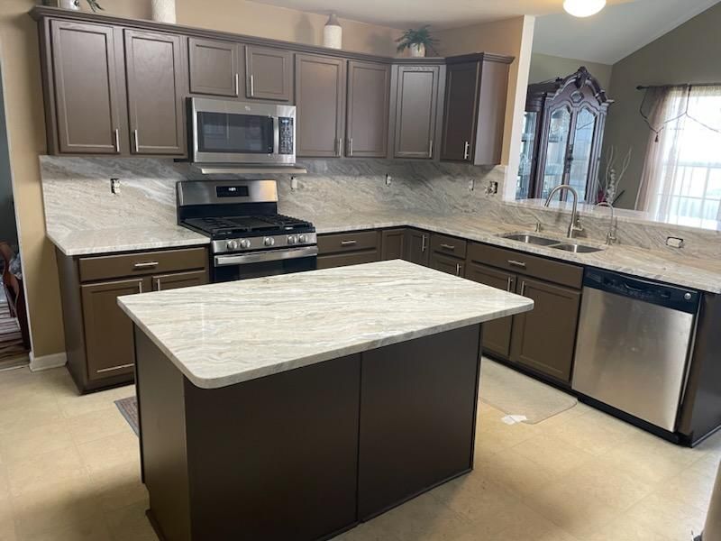 A kitchen with stainless steel appliances and a large island in the middle.