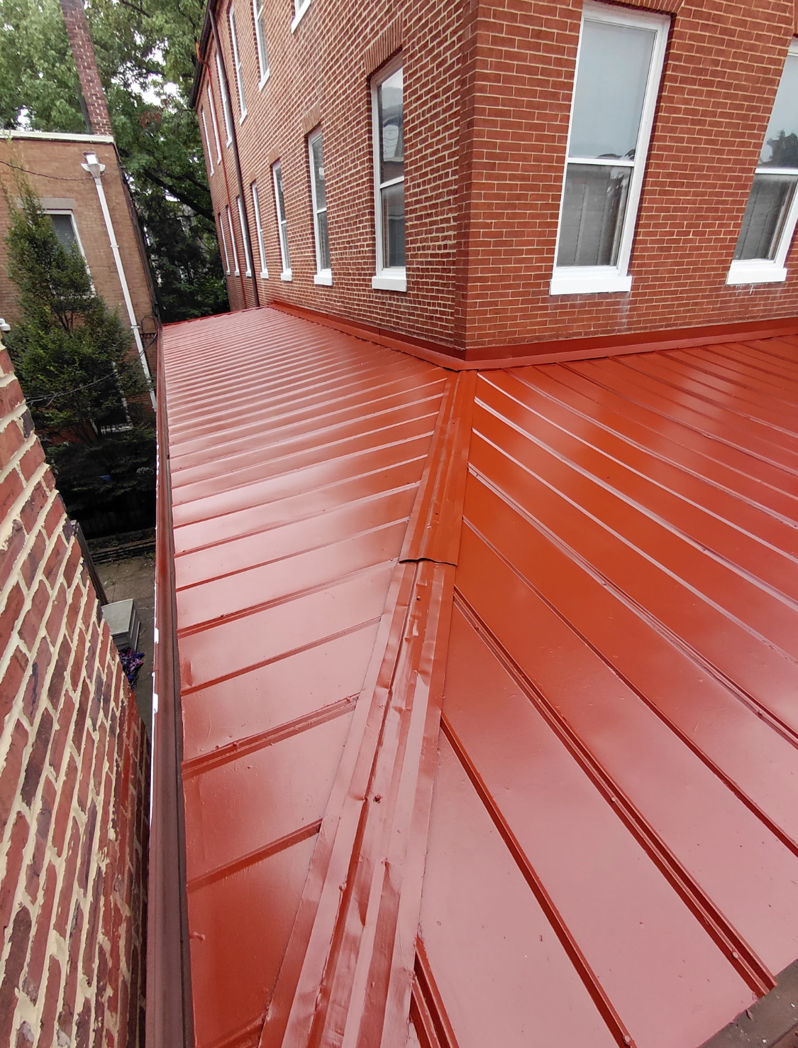 Red metal roof on a brick building, angled perspective.