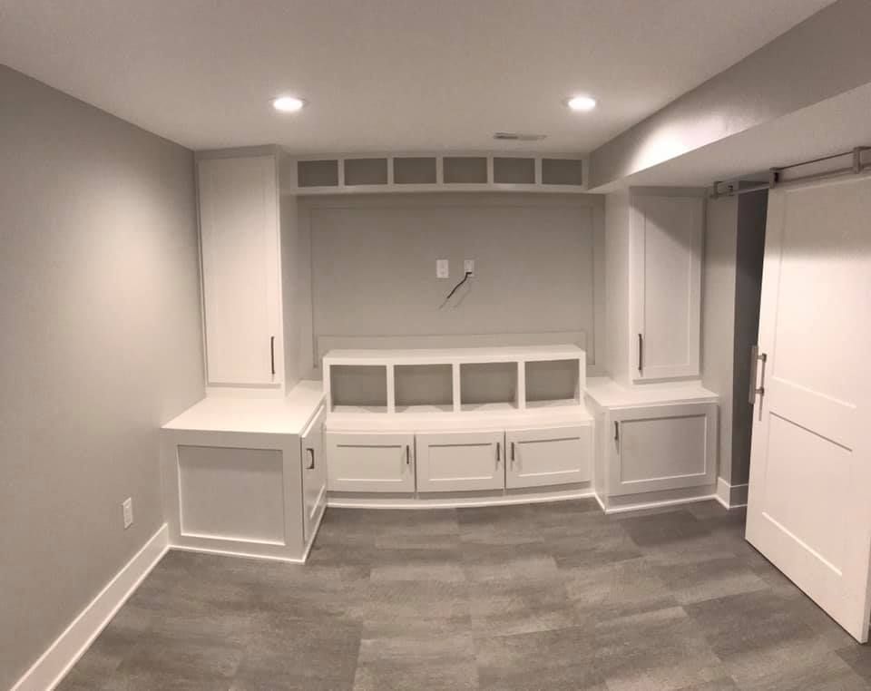 White built-in cabinetry in a room with gray walls and flooring; a sliding door is visible.