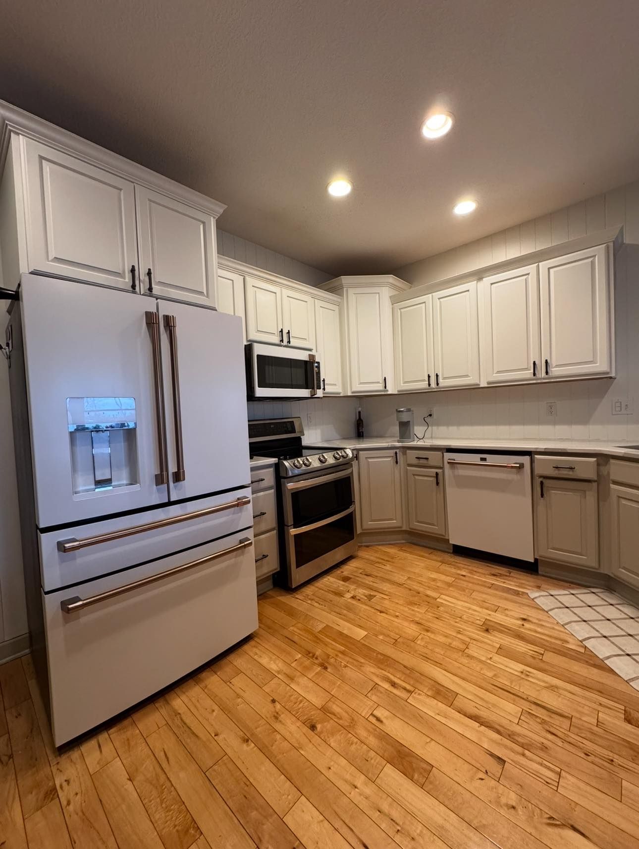 Kitchen with light wood floors, white cabinets, and stainless steel appliances.