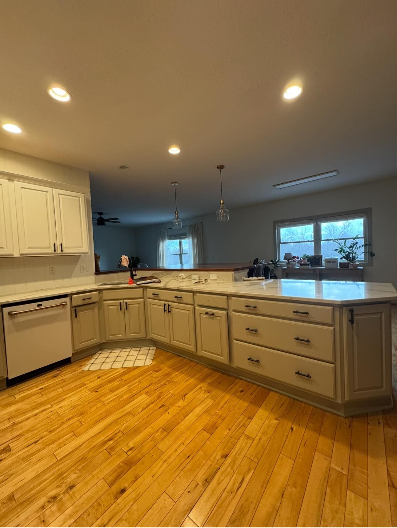 Bright kitchen with light wood floor, white cabinets, and island with countertop.