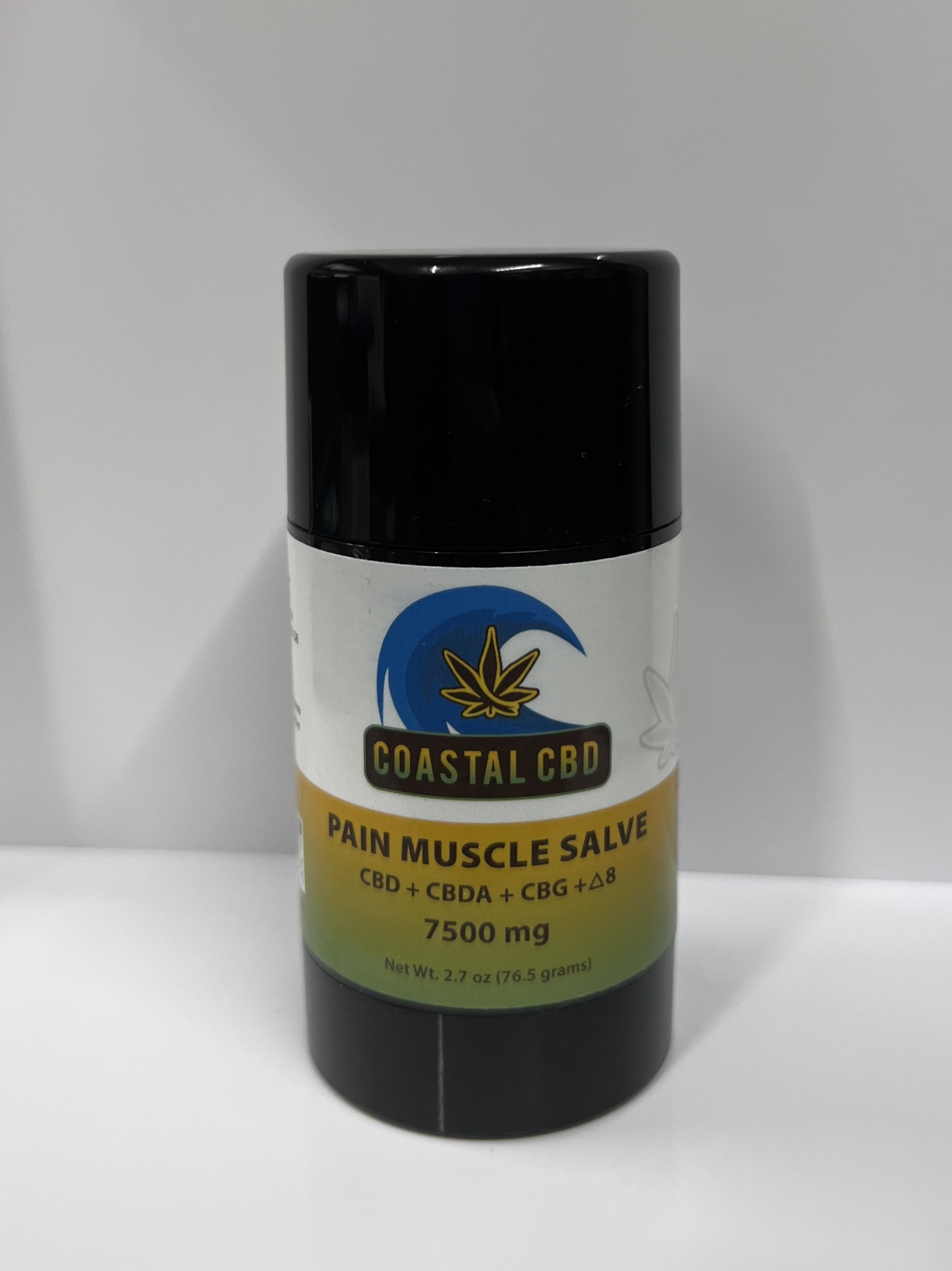 A bottle of coastal cbd pain muscle salve is sitting on a white surface.