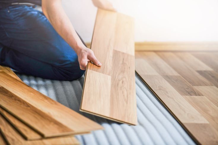 A person is installing a wooden floor in a room.