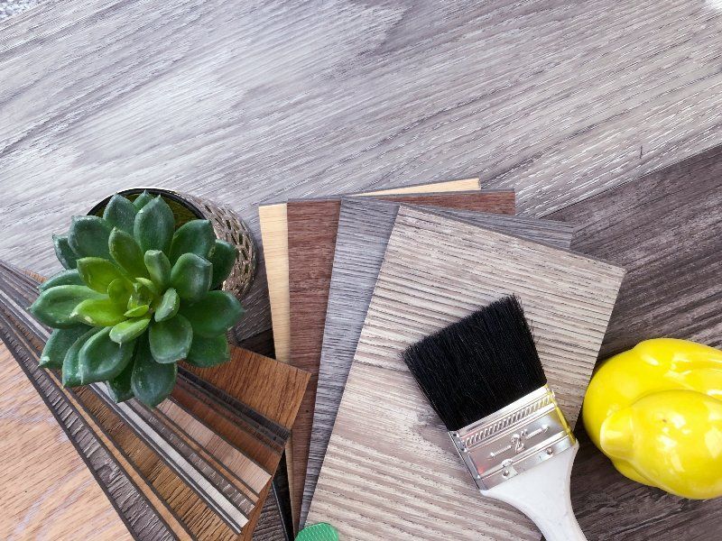 A brush is sitting on top of a wooden table next to a plant and a yellow pepper.