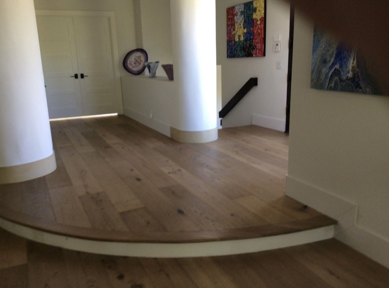 A hallway with a wooden floor and stairs in a house