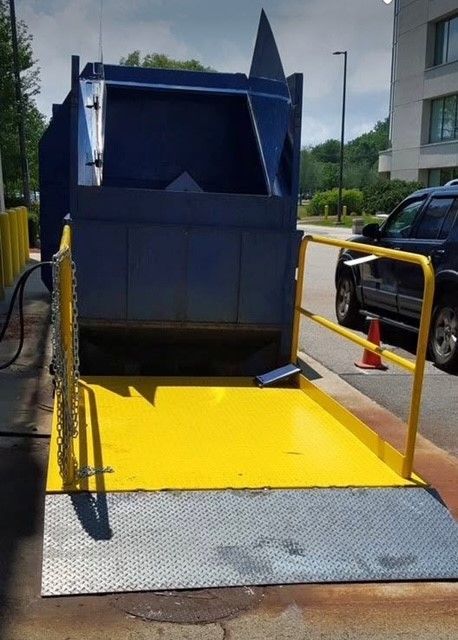 A blue dumpster is sitting on a yellow loading dock