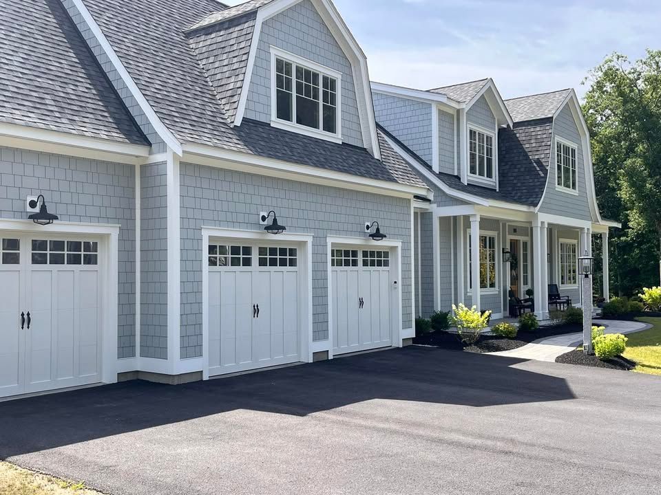A house with three garage doors and a driveway in front of it