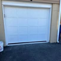 A white garage door is sitting in the driveway of a house