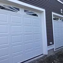 A pair of white garage doors on the side of a house