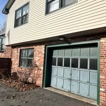 A house with a blue garage door and a brick wall