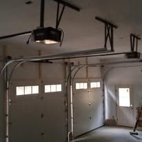 A garage door opener is hanging from the ceiling of a garage