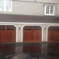 A house with three wooden garage doors on a rainy day